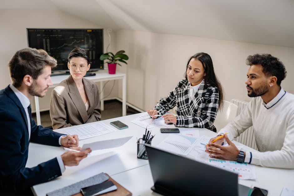A diverse group of professionals collaborating in an office setting, engaged in a meeting around a table.